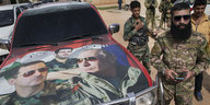 Soldaten stehen neben einem Auto, auf dem Bilder von Assad und Putin aufgeklebt sind