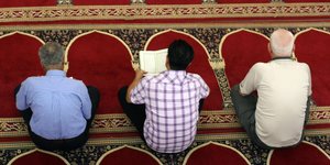 Drei Männer beten in einer Moschee