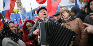 Ein Mann spielt Akkordeon auf dem Roten Platz in Moskau, drumherum stehen ihm zuhörende Menschen