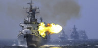 Ein Militärboot feuert übers Meer, im Hintergrund drei weitere Militärboote