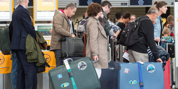 Menschen mit Koffer stehen in einer Schlange am Flughafen