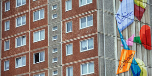 Wohnhaus in Plattenbauweise mit einem Wandbild auf dem „Schöner wohnen“ steht