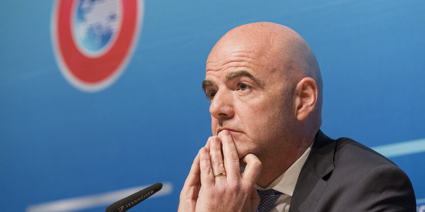 Infantino sitz mit ernstem Gesichtsausdruck vor einem Mikrofon, im Hintergrund UEFA-Logo