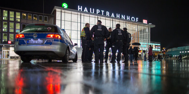 Vor dem Kölner Hauptbahnhof stehen mehrere Polizisten neben einem Polizeiwagen