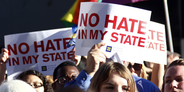 Demonstrant_innen halten Schilder mit der Aufschrift „No hate in my state“ hoch