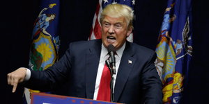Donald Trump spricht und gestikuliert hinter einem Podium