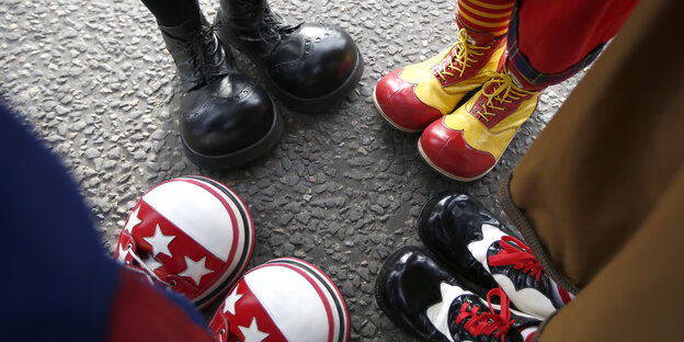 Vier Paar Füße mit Clownsschuhen