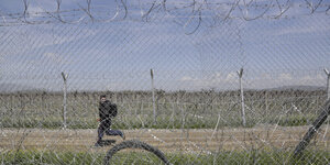 Ein junger Flüchtling rennt am Zaun an der mazedonisch-griechischen Grenze entlang