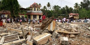 Menschen bewegen sich zwischen den Trümmern des durch die Explosion zerstörten Tempels