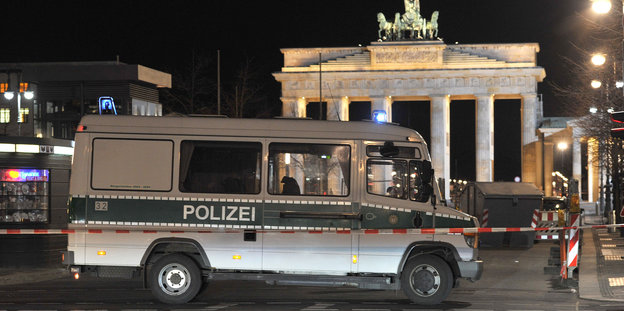 Polizeifahrzeug hinter einem rot-weißen Absperrband nachts vor dem Brandenburger Tor in Berlin