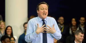 Ein Mann hält seine Hände vor die Brust, es ist David Cameron