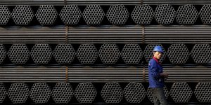 Ein chinesischer Arbeiter geht an einem Depot mit Stahlstangen vorbei