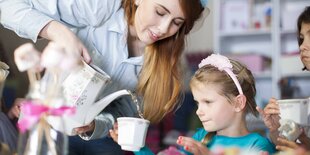 Eine Frau gießt ihrer Tochter eine Tasse Tee ein