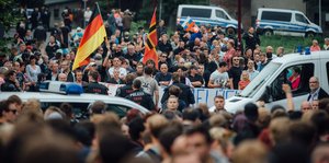 Viele Menschen mit einer Deutschlandfahne und der Flagge Deutscher Widerstand 20. Juli. Davor Polizeikräfte