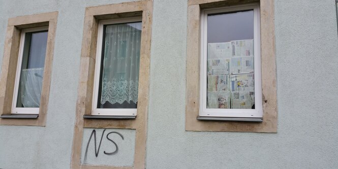 Fensterfront, unter einem Fenster eine Hakenkreuzschmiererei