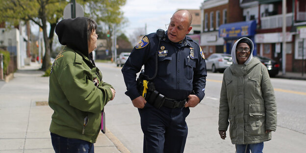 Der Polizist Ken Hurst mit zwei Menschen auf einer Straße in der US-Stadt Baltimore