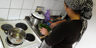 Eine Frau steht vor einem Herd und bereitet Essen vor