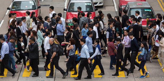 Viele Menschen laufen über die Straße in Hongkong