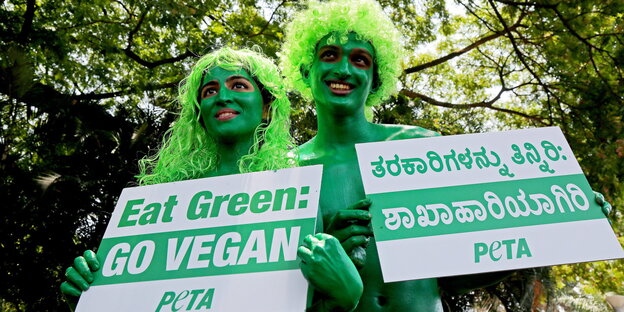 Peta-Aktivisten halten Pro-Vegan-Plakate in die Kamera