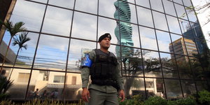 Ein Polizist mit schusssicherer Weste steht vor dem spiegelverglasten Bürogebäude von Mossack Fonseca