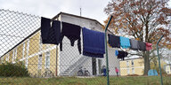 Kleidung hängt auf einem Zaun vor Gebäuden
