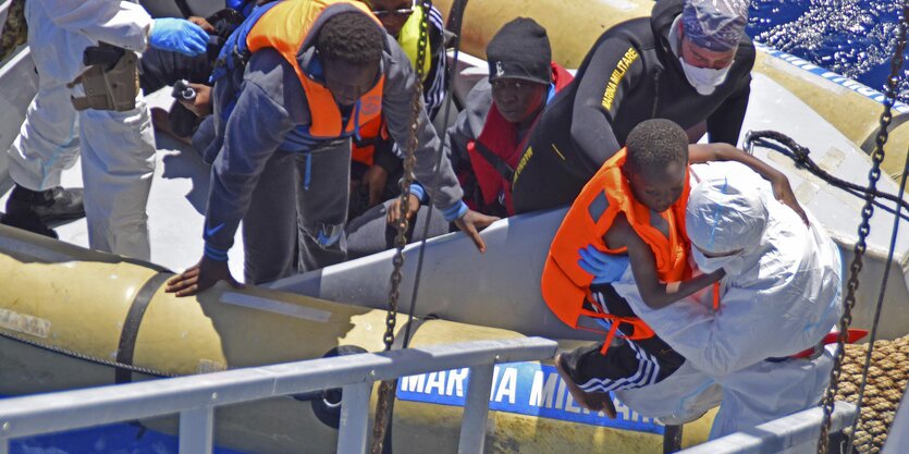 Menschen steigen aus einem Boot auf ein Schiff