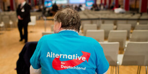 Der Rücken eines älteren Mannes mit AfD-Hemd in einem leeren Sitzungssaal