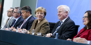 Sechs Personen sitzen auf einem Podium