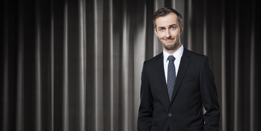 Moderator Jan Böhmermann im Anzug vor einem Vorhang