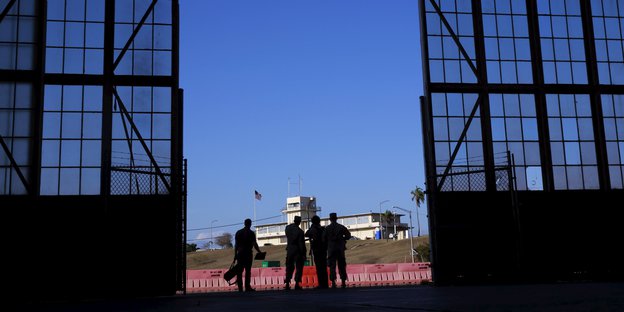 Schatten von vier Menschen im Tor zu einer Gefangenenanstalt