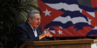 ein Mann mit erhobenem Zeigefinger an einem Rednerpult; im Hintergrund einer kubanische Fahne