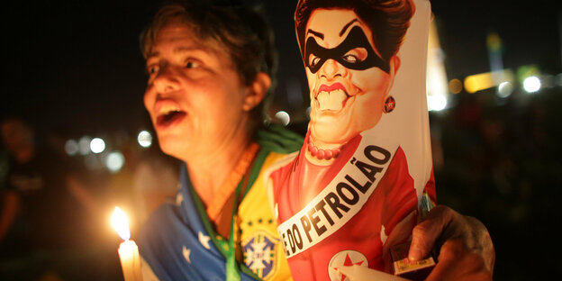 Eine Protestlerin, sie hält Kerzen und ein Schild mit Dilma Rousseff