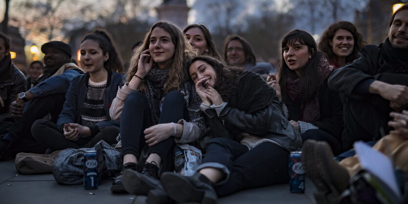 Junge Menschen sitzen auf dem Boden