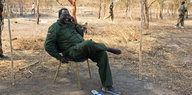 Riek Machar sitzt auf einem Stuhl und telefoniert.