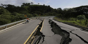 Ein Mann auf einem Motorroller fährt auf einer vom Erdbeben aufgerissene Straße in Ecuador