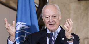 Staffan de Mistura steht hinter einem Mikrofon und hebt die Hände