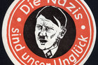 Ein Sticker zeigt in schwarz-rot ein Porträt von Adolf Hitler, im Kreis darum steht „Die Nazis sind unser Unglück“