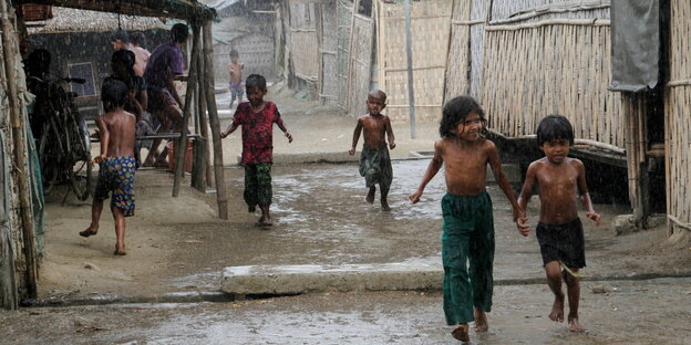 Rohingya-Kinder laufen in einem Camp nahe Sittwe im Westen Myanmars durch den Regen.
