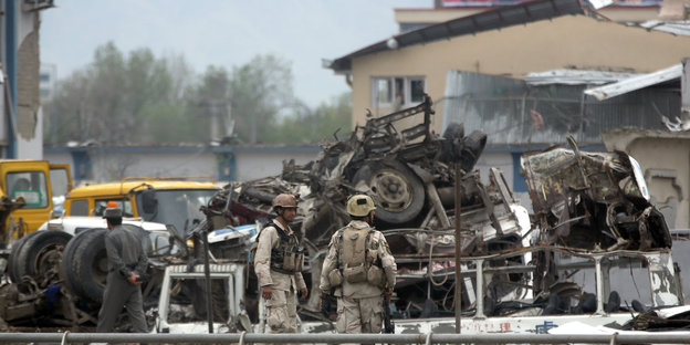 Soldaten stehen vor einem zerstörten Lastwagen