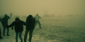 Mehrere Personen laufen im Nebel über ein Feld