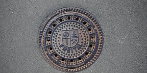 Ein Gullydeckel mit dem Wappen der Stadt Freital
