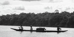 Drei Männer fahren in einem Boot auf dem Amazonas.