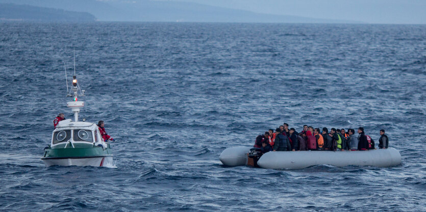 Ein Schlauchboot mit vielen Menschen, daneben ein größeres Boot