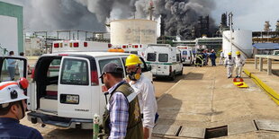 Eine Chemiefabrik in Coatzacoalcos, im Hintergrund schwarzer Rauch, im Vordergrund Einsatzkräfte