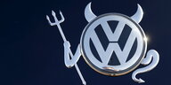 Ein VW-Logo, verziert mit Teufelshörnern, Schwanz und Dreizack