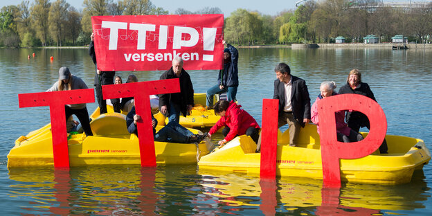 In zwei gelben Schlauchbooten sitzen mehrere Aktivisten, die rote Buchstaben in der Hand haben. Sie ergeben das Wort TTIP