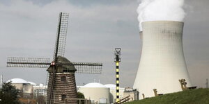 eine alte Windmühle und ein rauchender Kühlturm