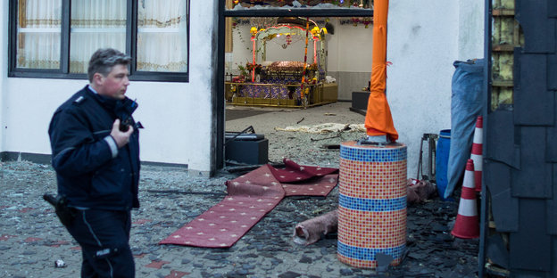 Ein Polizist steht vor dem zerstörten Sikh-Tempel in Essen