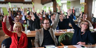 Ein Saal mit Menschen, die grüne Stimmkarten heben