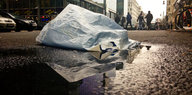 Eine Plastiktüte auf regennasser Straße